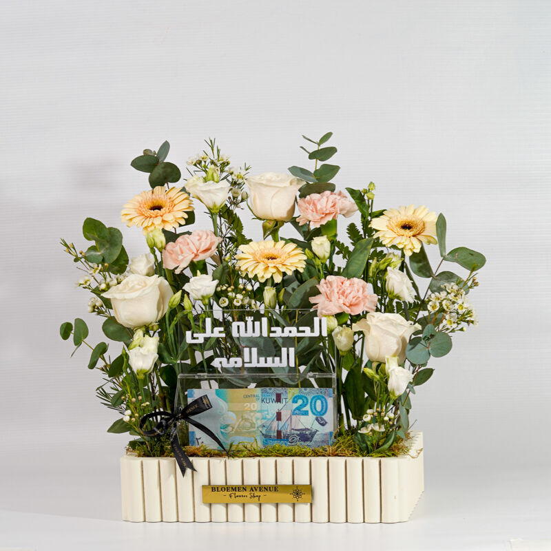 A wooden box with mixed flowers containing an empty money box with the words "Praise be to God for safety" M43