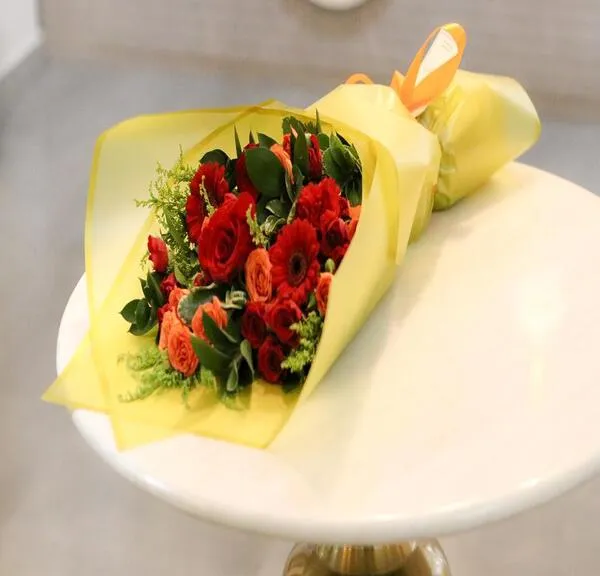 Hand Bouquet of Red and Orange Flowers in Golden packaging . H11