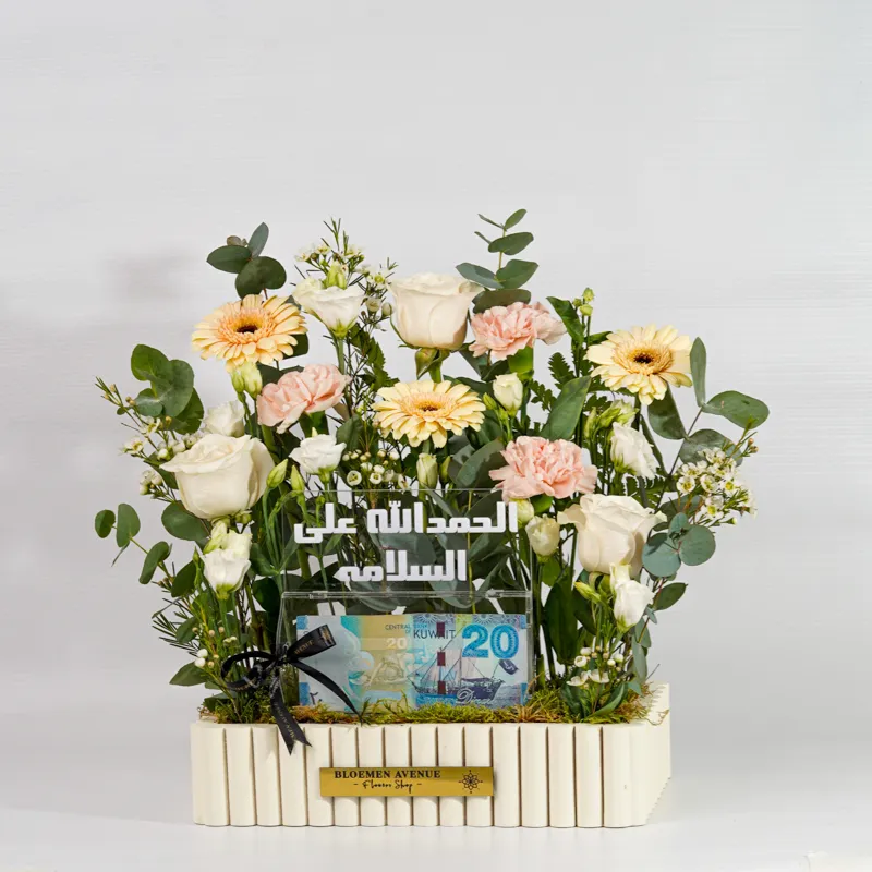 A wooden box with mixed flowers containing an empty money box with the words "Praise be to God for safety" M43